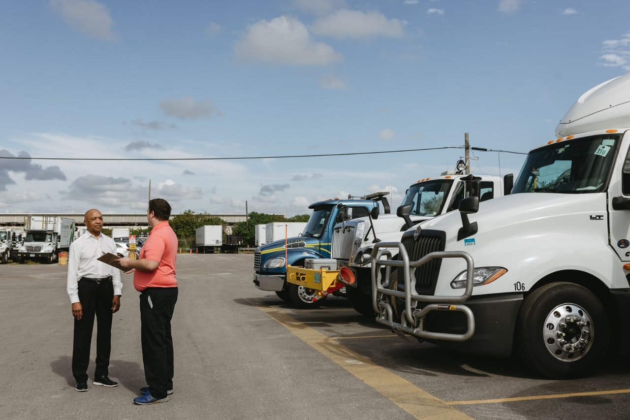 Sun State team members reviewing rental equipment with a clipboard beside a row of trucks