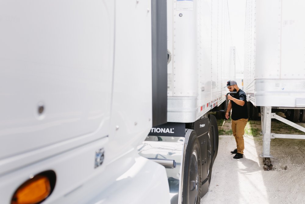 Technician inspecting a dry van trailer's rear hitch and undercarriage before resale