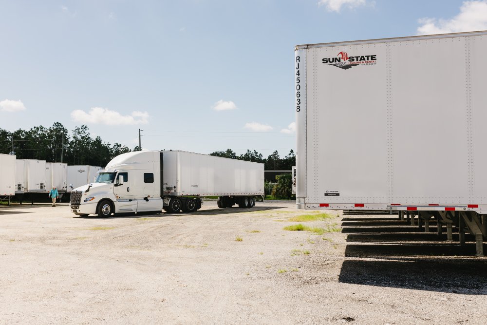 Sun State branded dry van trailer parked next to an International tractor at the dealership lot