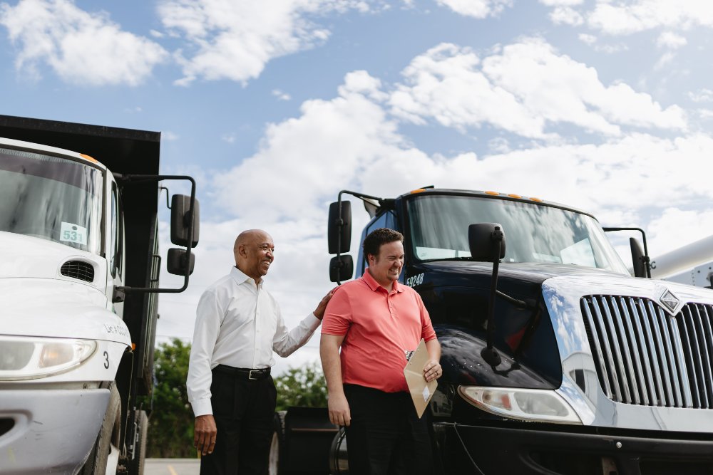 Sun State team members greeting a customer beside International trucks at the dealership