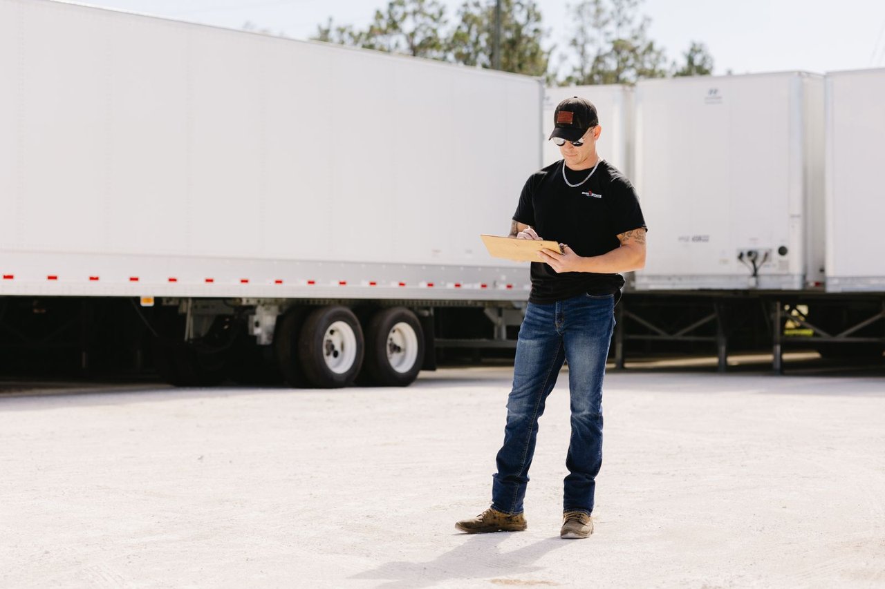 Sun State technician performing a pre-trip inspection on a reefer trailer with a clipboard