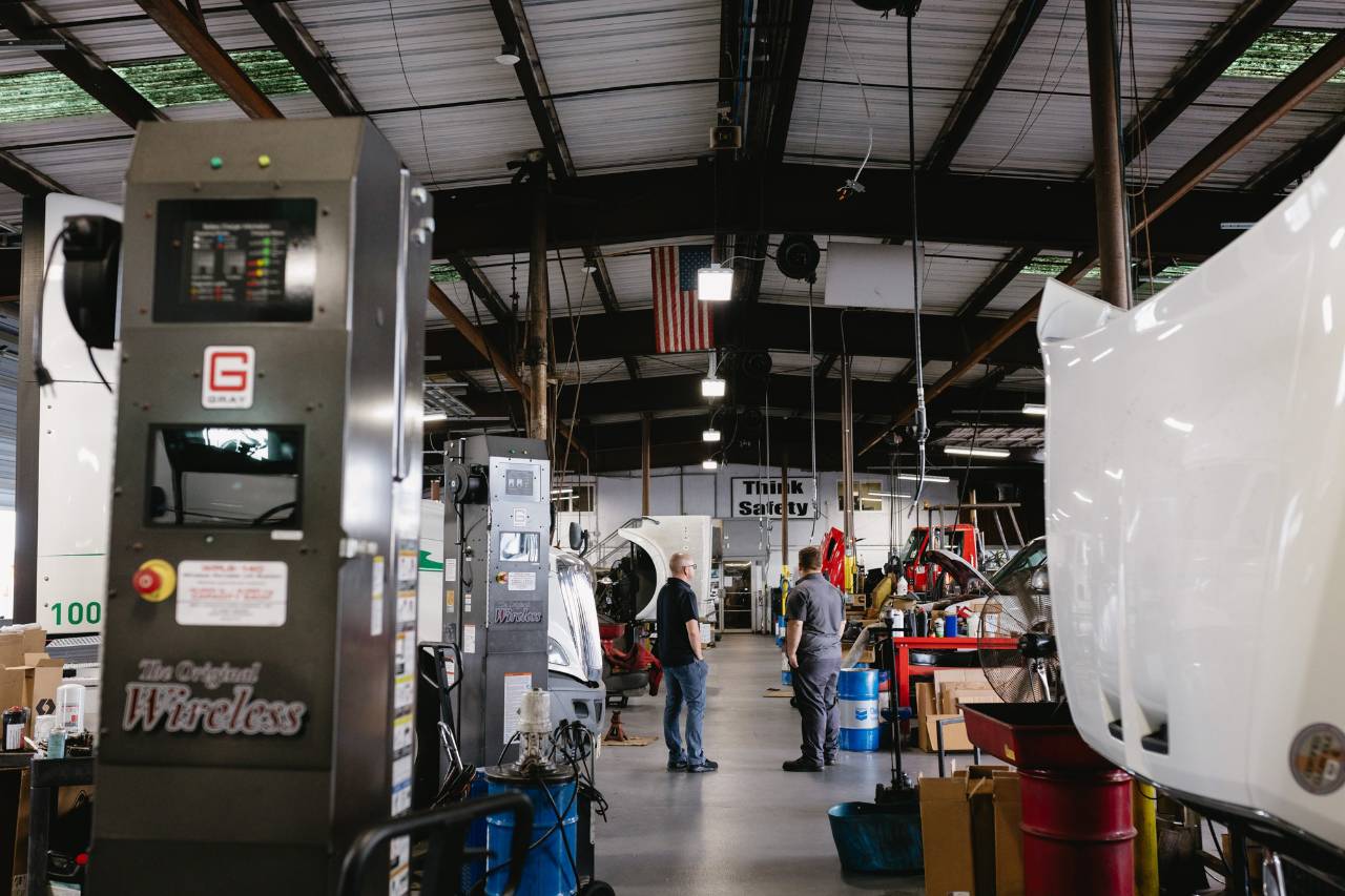 Sun State International team members standing among commercial trucks in the service shop