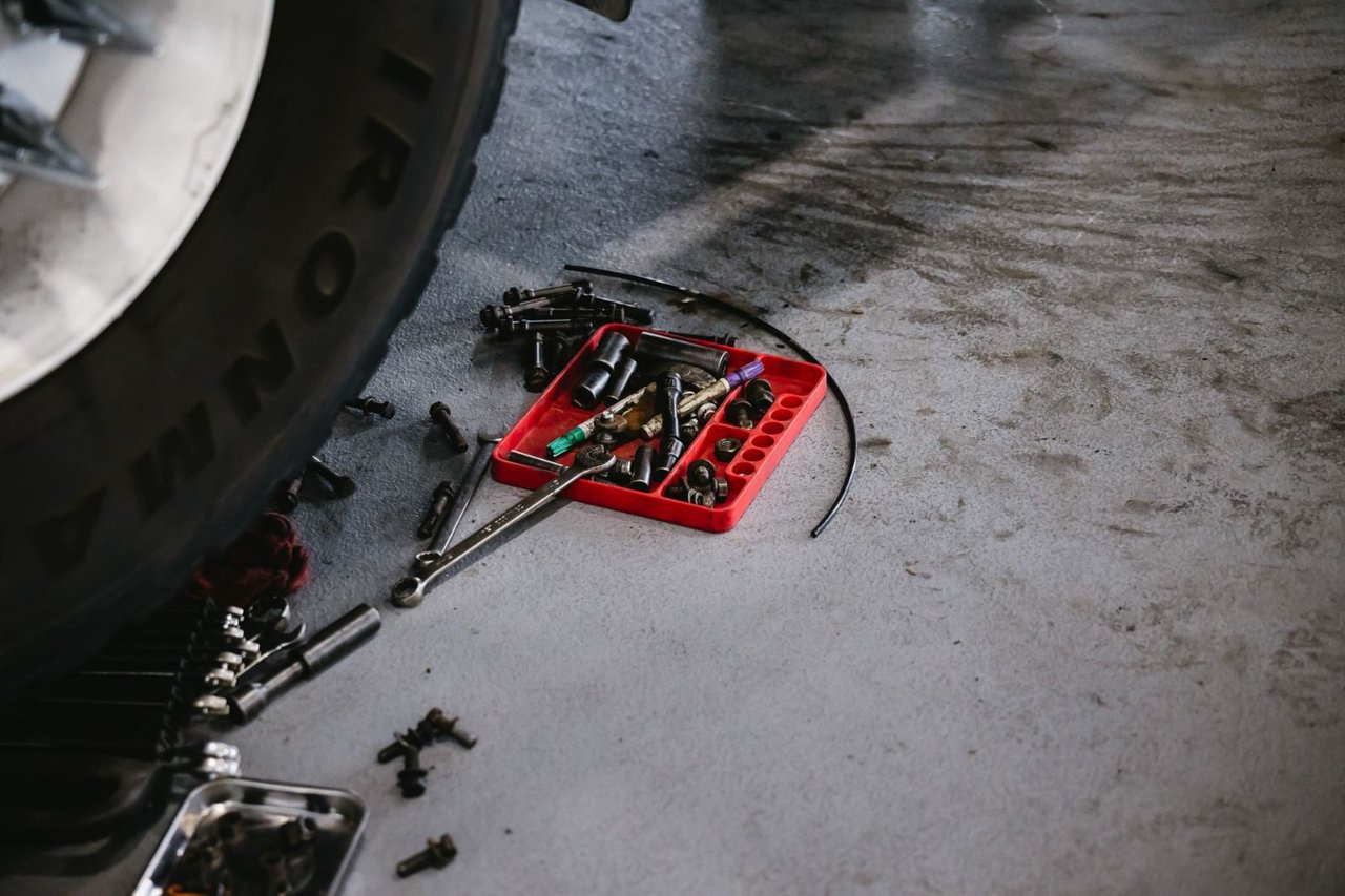 Sockets, wrenches, and brake hardware laid out beneath a trailer wheel during service