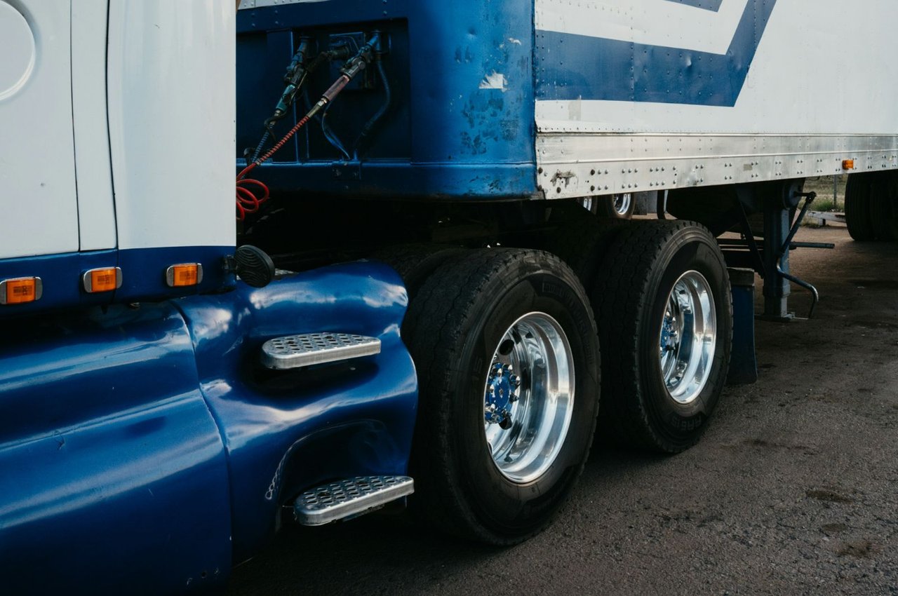 Close-up of a blue trailer's rear axle assembly and tires