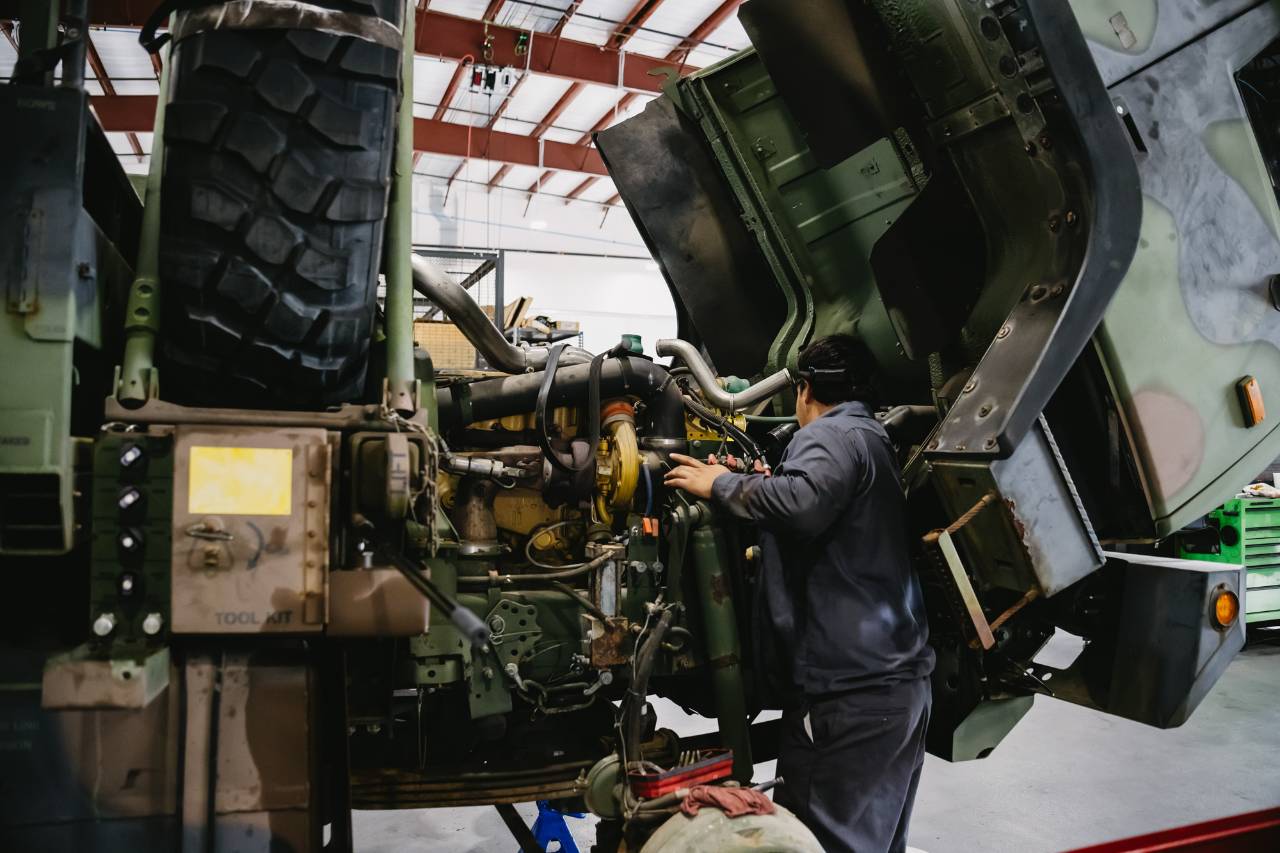 Sun State International technician installing OEM truck parts on a service bay engine
