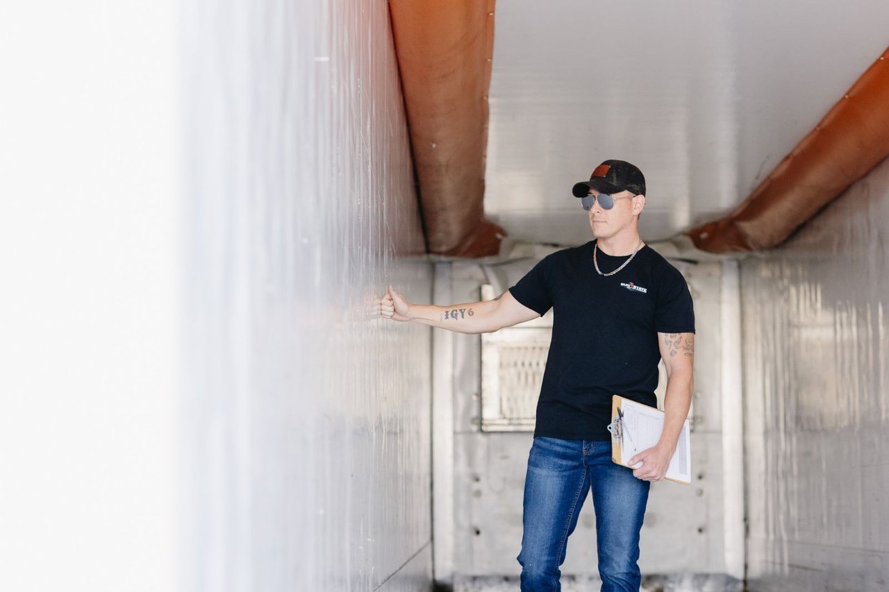 Sun State technician inspecting the interior wall of a trailer with a clipboard