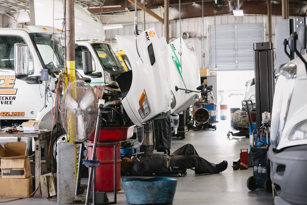 Technician performing a preventive maintenance inspection underneath a truck in the Sun State International service bay