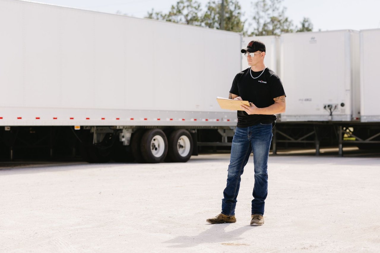 Sun State technician taking notes on a clipboard near a row of trailers