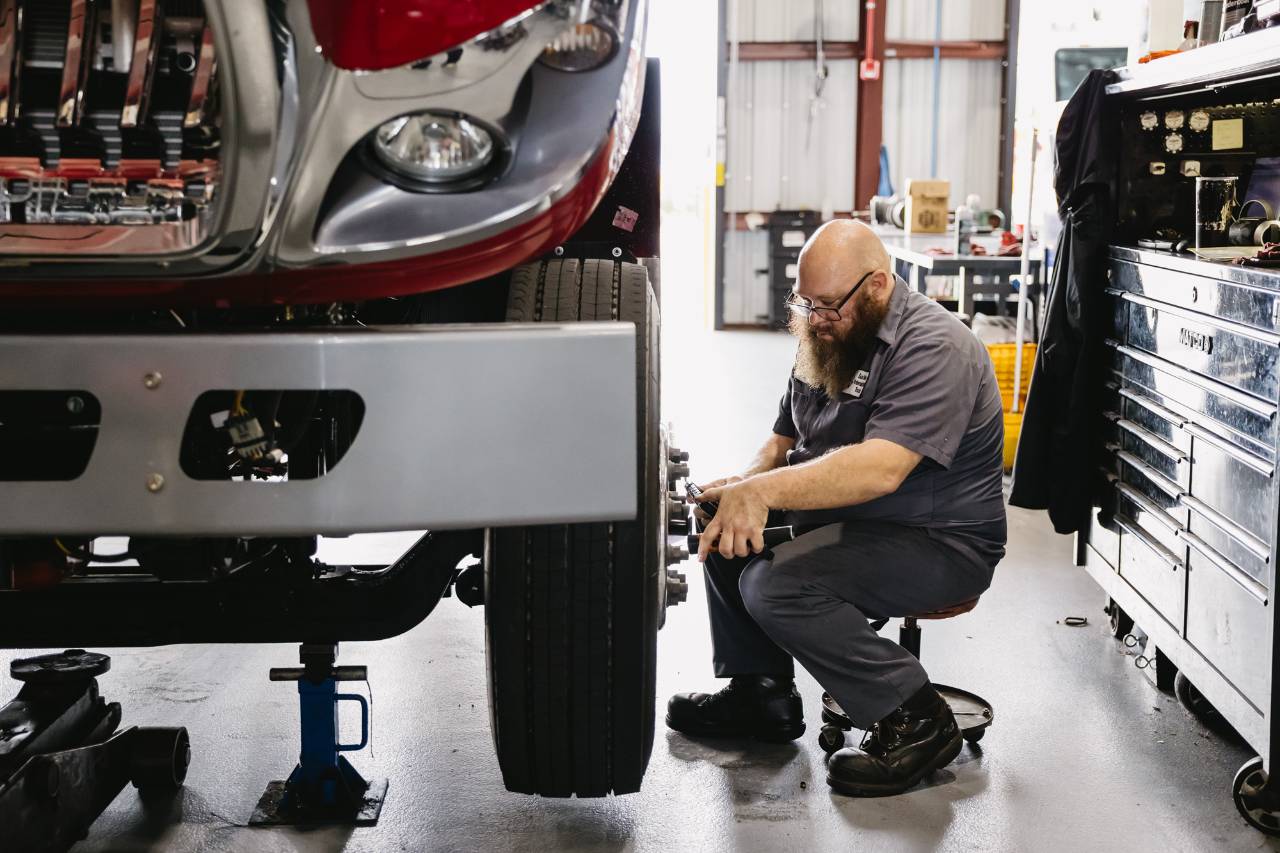 Sun State International technician performing a preventive inspection on a semi truck's front axle