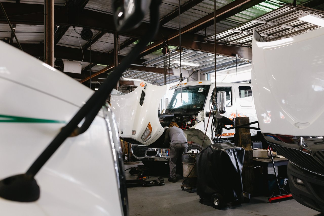 Technicians working on International trucks with hoods raised inside the Sun State service bay